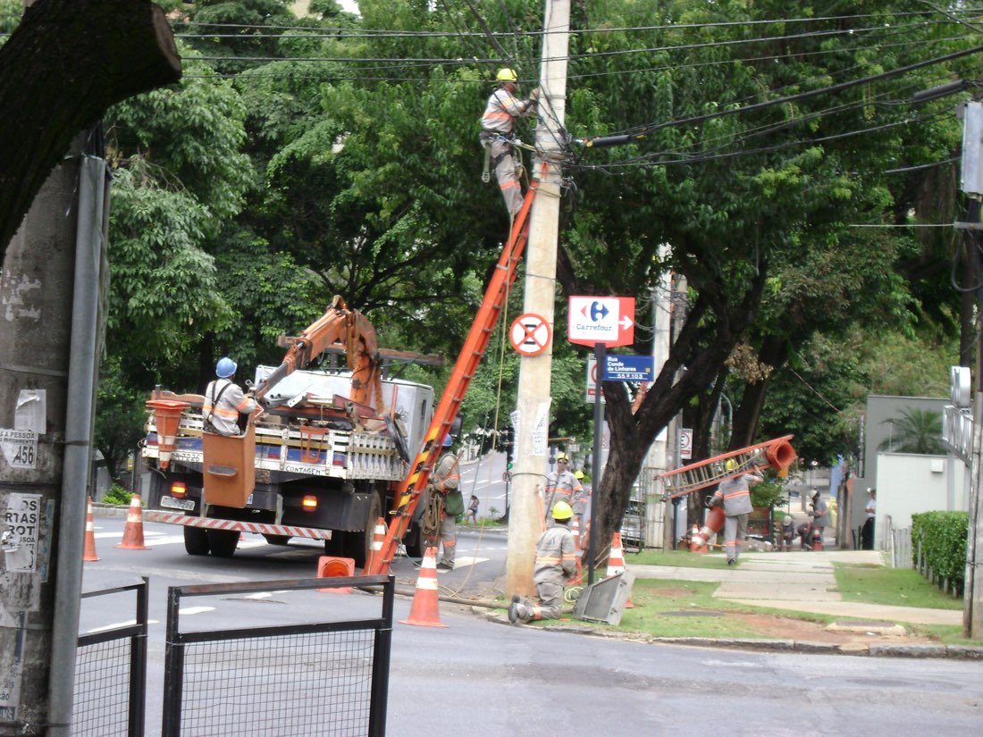 Equipe de eletricistas trabalhando em um poste de energia em Belo Horizonte, com caminhão e cesto aéreo, exemplo de prestador de serviço de campo no Brasil que precisa calcular o custo da hora-técnica